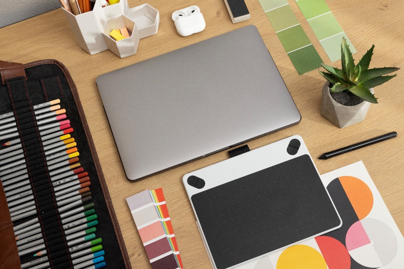 Bureau de designer avec des échantillons de couleurs, un ordinateur portable et une tablette graphique.