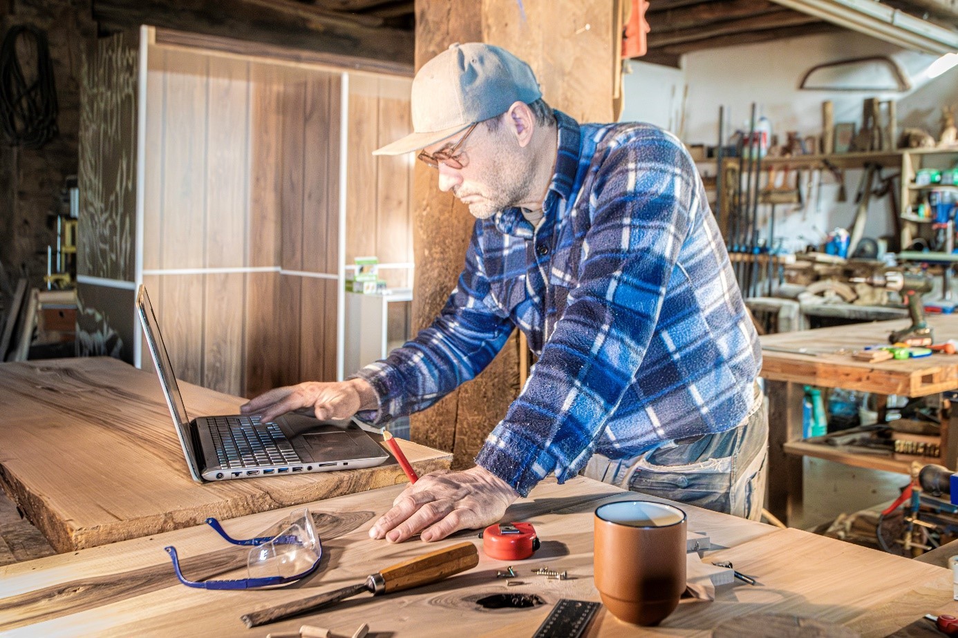 Artisan menuisier utilisant un ordinateur portable dans son atelier.