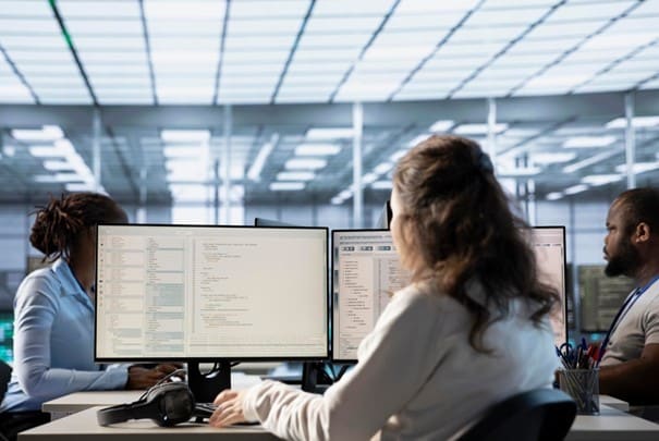 Équipe de développeurs travaillant sur plusieurs écrans dans un bureau moderne.